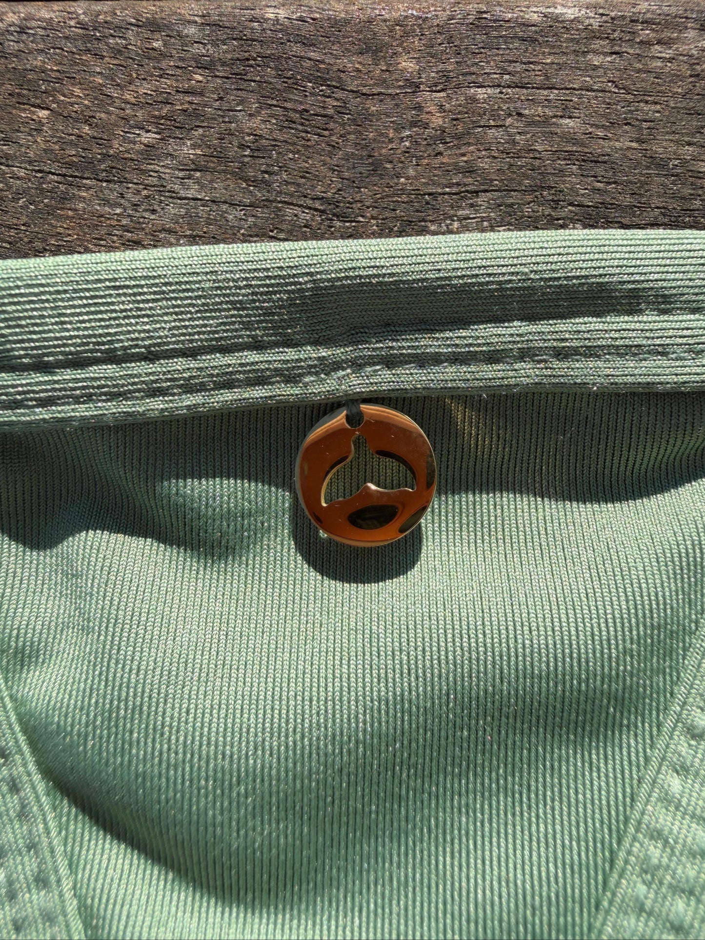 Close-up of a green fabric with a brown button on a wooden surface